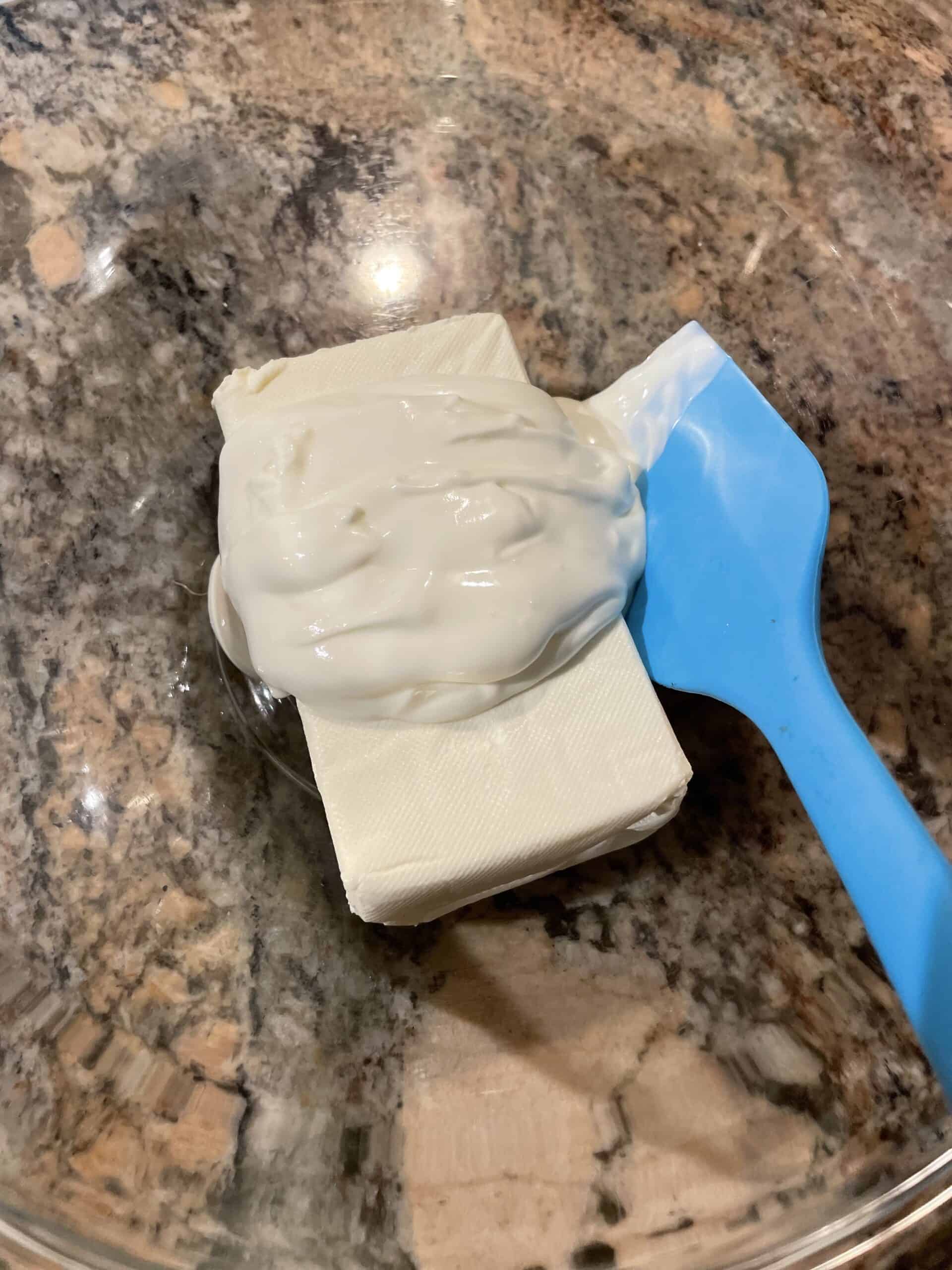 Softened Cream Cheese and Sour Cream in a bowl with a spatula.