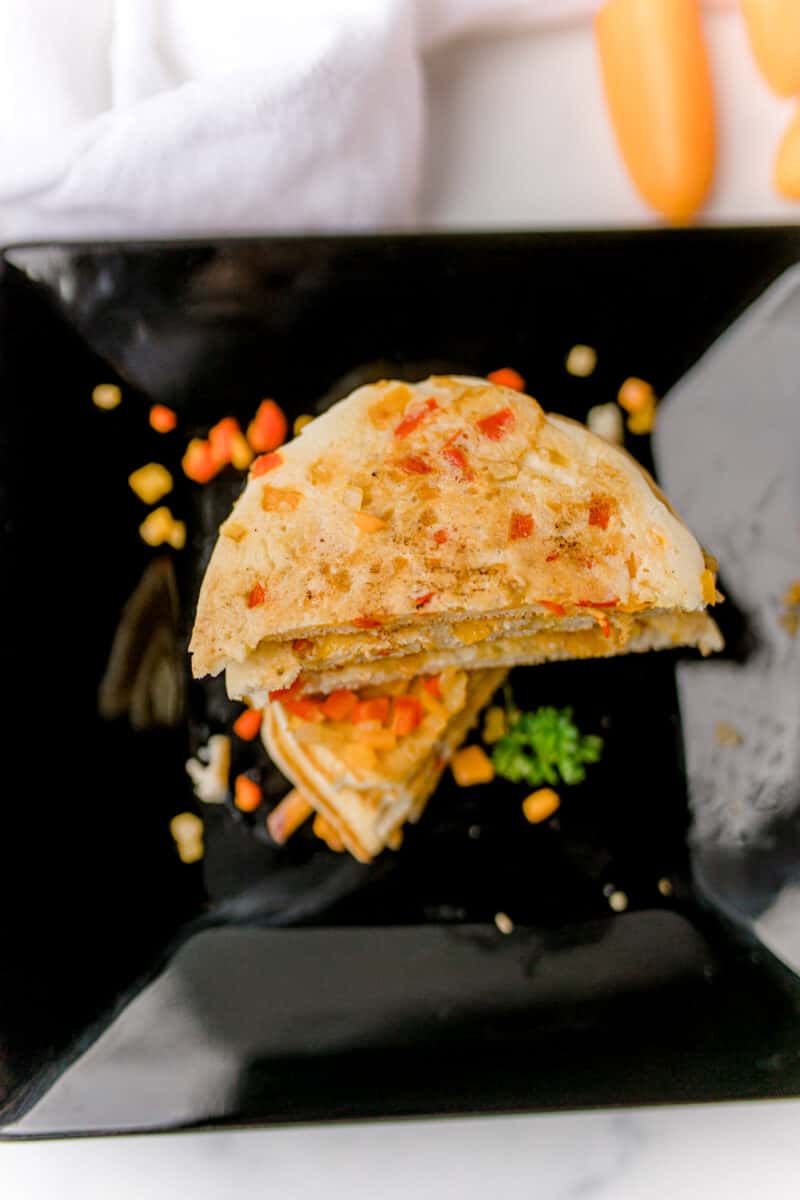 Savory Pancakes Recipe on a black plate with a sprinkle of diced peppers.