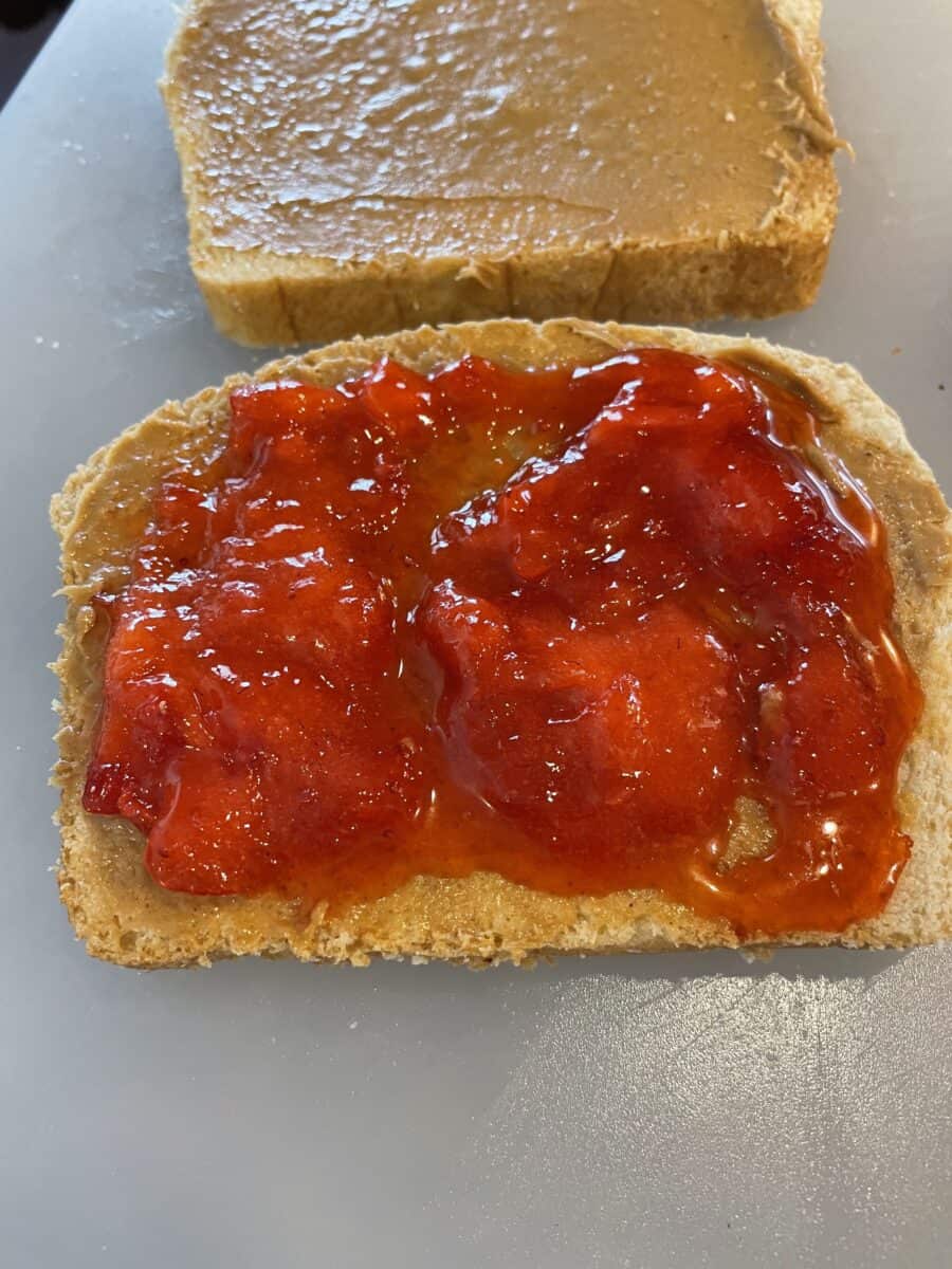 A Layer of Strawberry Jam on one Slice of Peanut Buttered Bread.