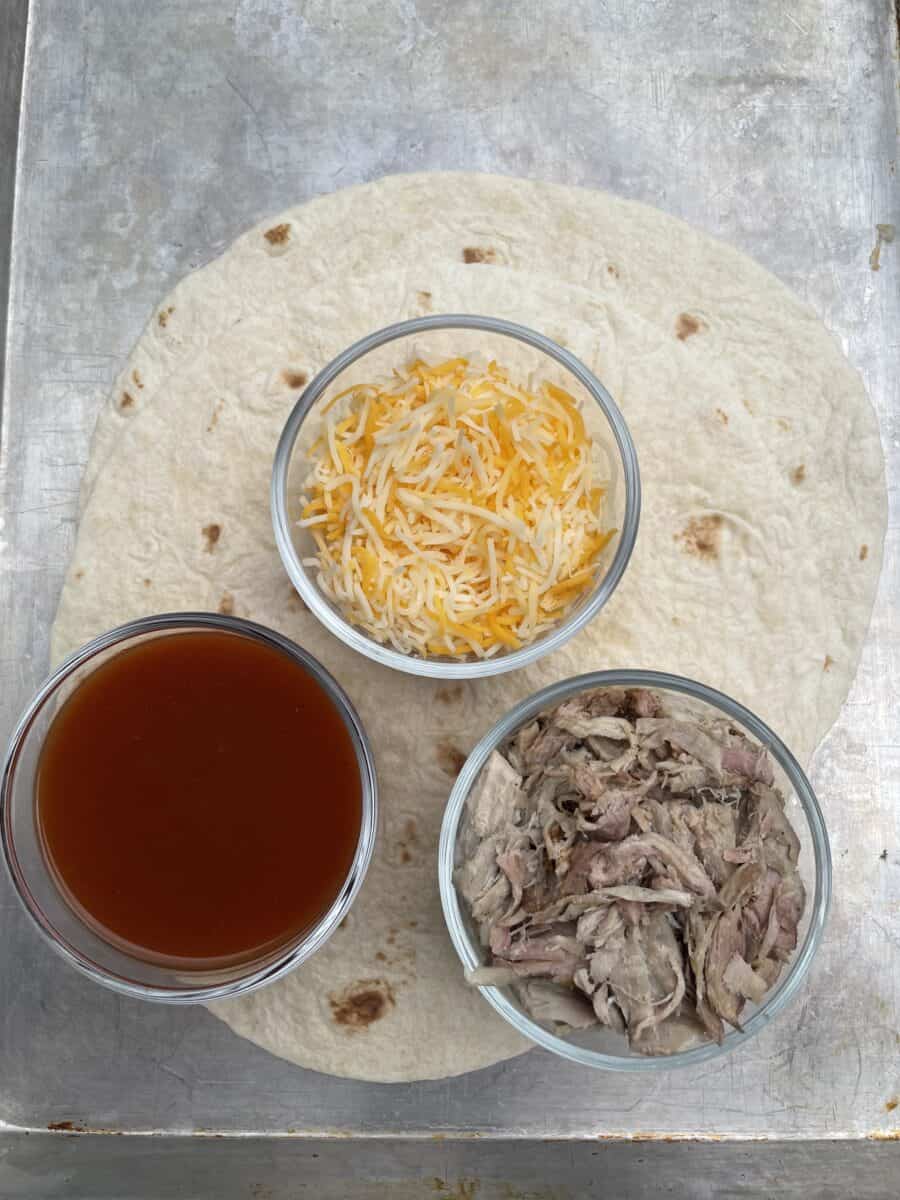 Pulled Pork Burrito Ingredients - Flour Tortilla Shell, Shredded Cheese, Pulled Pork, and red enchilada sauce. 