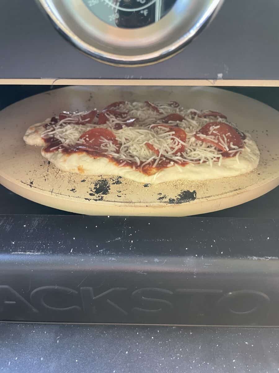 A Homemade Pepperoni Pizza Cooking in a Blackstone Pizza Oven.