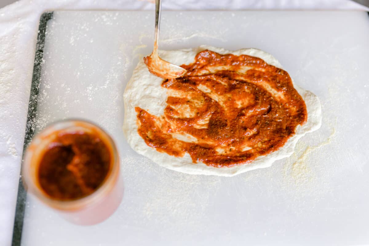 Best Pizza Sauce spread on the top of a homemade pizza crust.