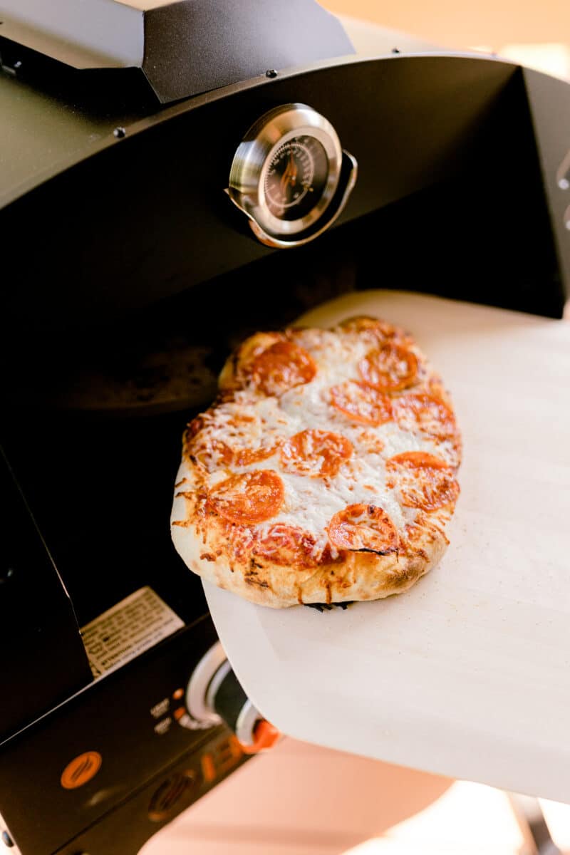 Using a Pizza Peel to remove a cooked pepperoni pizza from the hot oven.