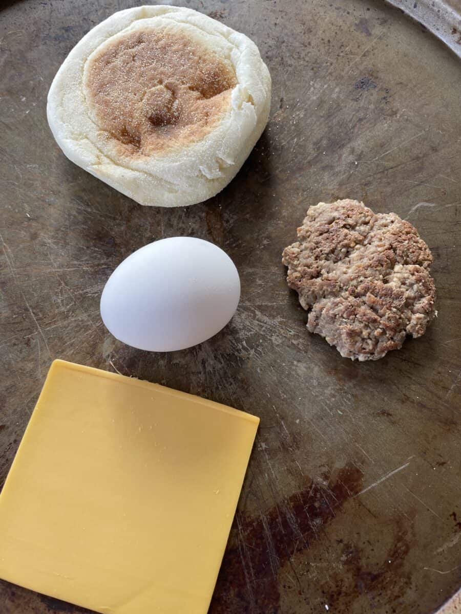 Sausage McMuffin Ingredients: Egg, English Muffin, Cooked Sausage Patties, and a Slice of American Cheese.