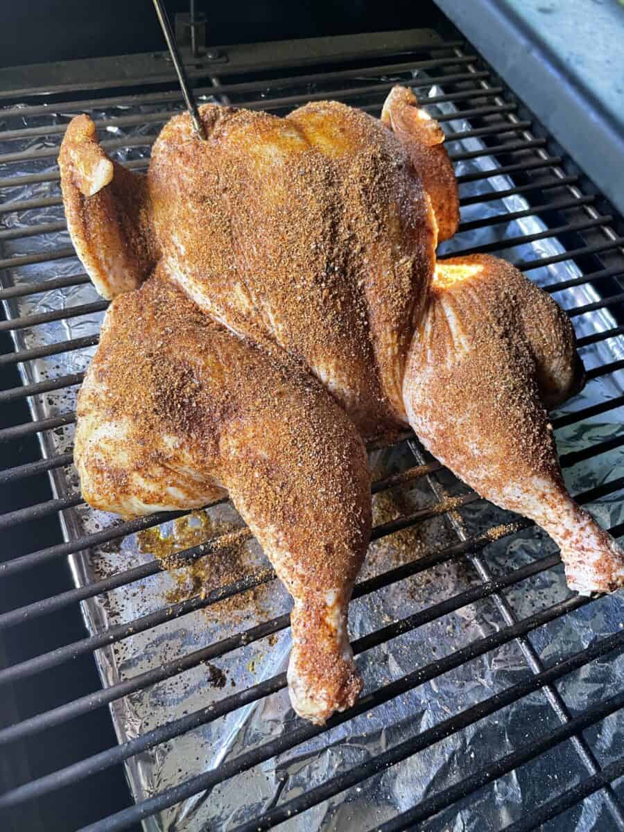 Placing the Seasoned Spatchcock Chicken on a Pellet Smoker.