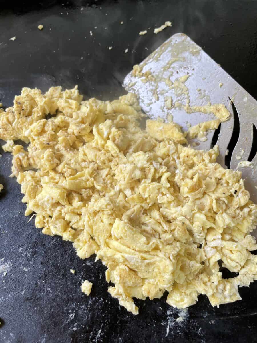 Scrambled Eggs on a Blackstone Griddle with a griddle spatula.