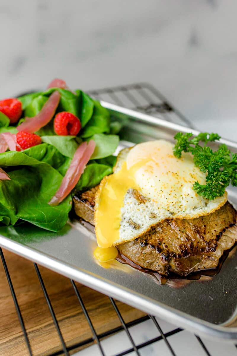 Topping a Griddle Cooked Steak with a Fried Egg along with a side salad.