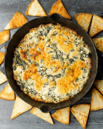 Smoked Cream Cheese Spinach Dip in a cast iron pan surrounded by toasted triangle chips.