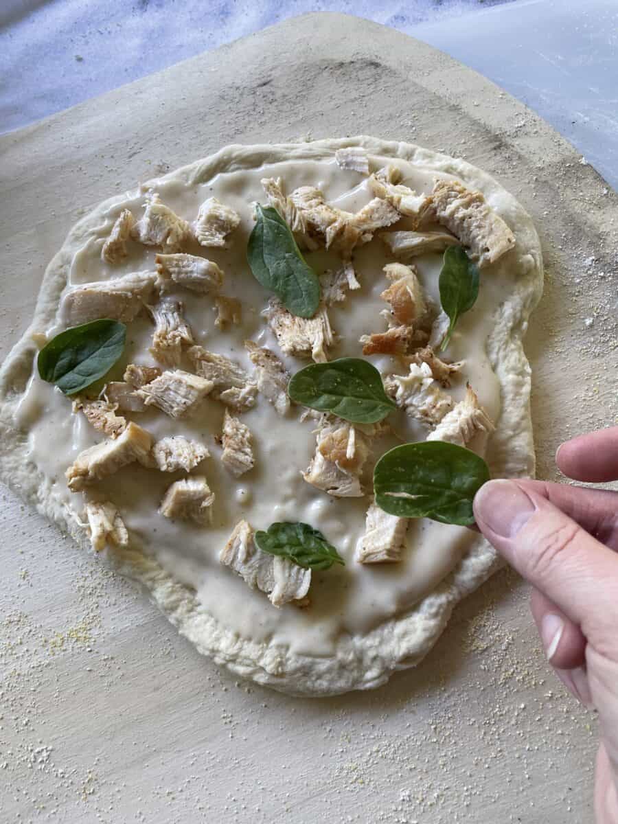 Topping a Chicken Alfredo Pizza with Fresh Herbs.