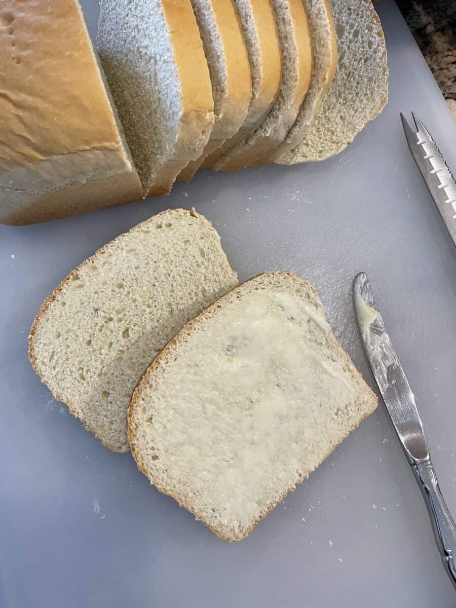 Homemade White Bread that is sliced and lightly buttered with a butter knife.  