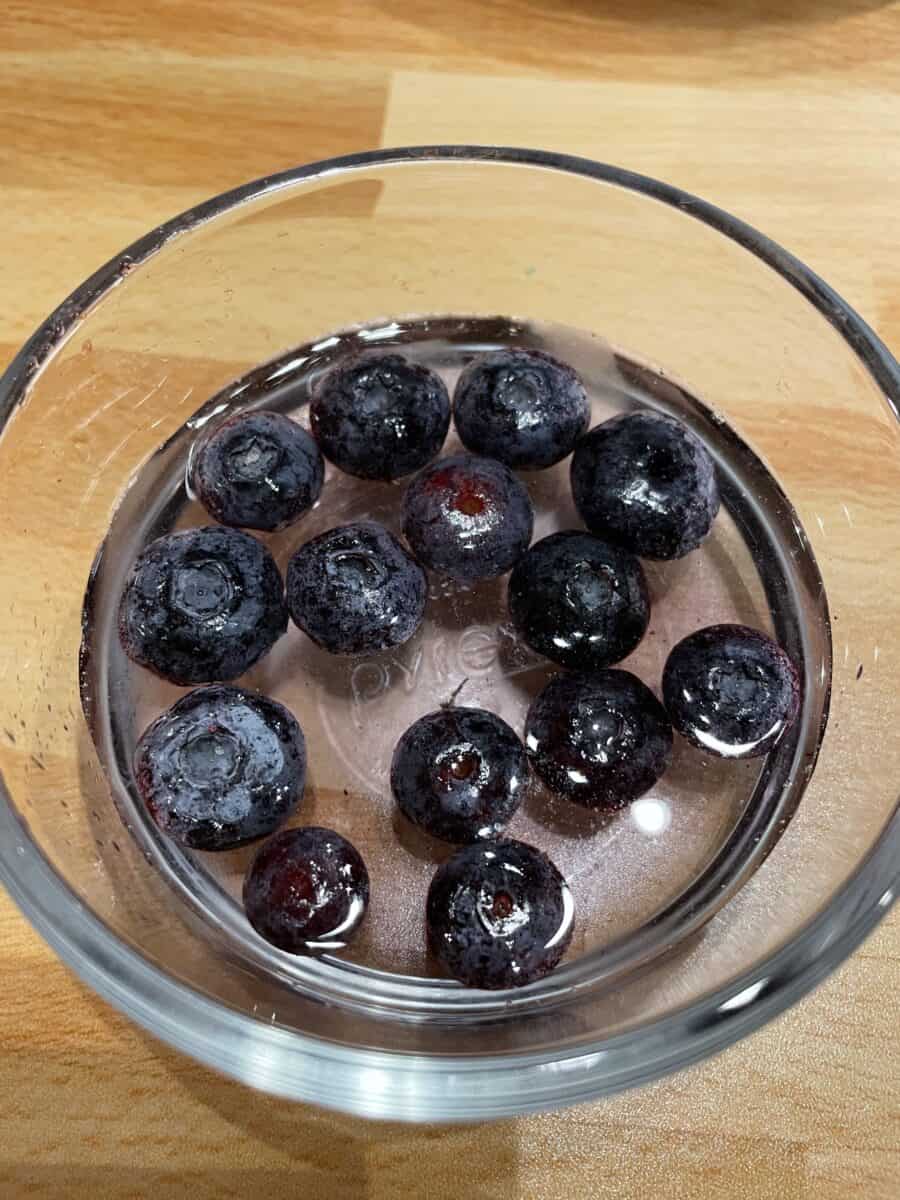 Frozen Blueberries Thawing in a Glass Bowl of Water.