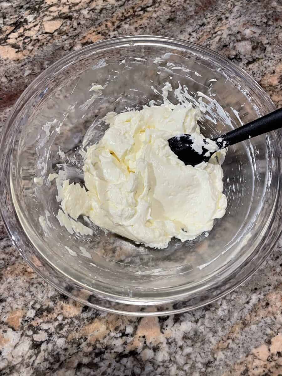 Stirring Softened Butter and Cream Cheese in a Mixing Bowl with a spatula.
