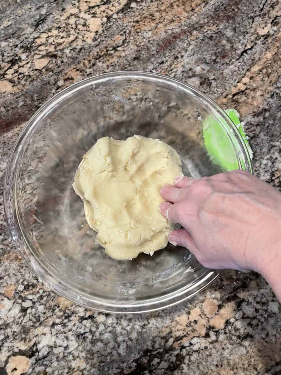 A Hand Poking A Sugar Cookie Dough Ball in a Mixing Bowl.