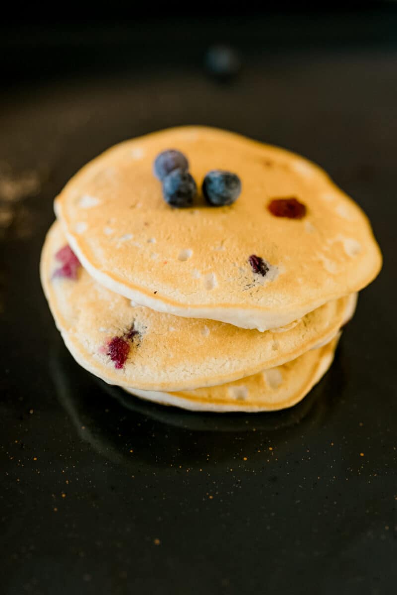 A Stack of Cooked Blueberry Pancake on Blackstone Griddle Garnished with Fresh Blueberries.