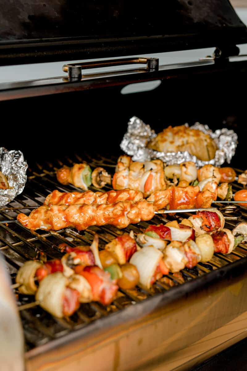 A Pellet Smoker with Several Different Kabobs and Smoked Hasselback Potatoes.