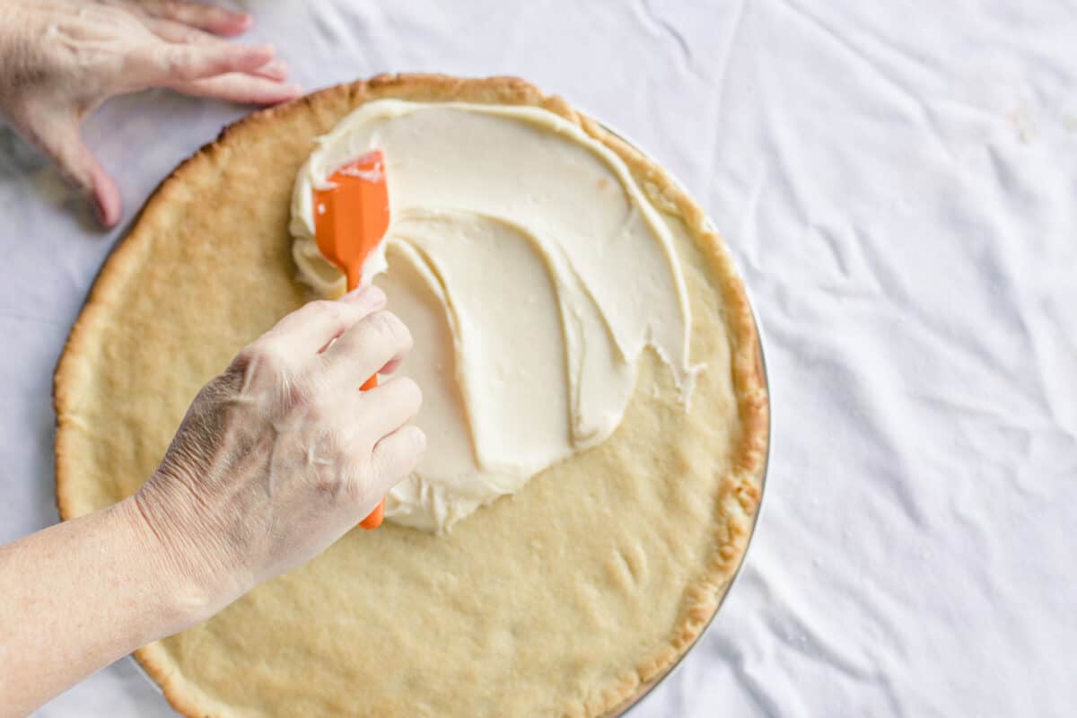 Spreading Cream Cheese Frosting with a Mini Silicone Spatula on top of a Baked Pizza Cookie Crust.