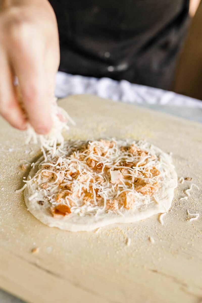 Sprinkle a Layer of Shredded Mozzarella Cheese onto the Salmon Pizza.
