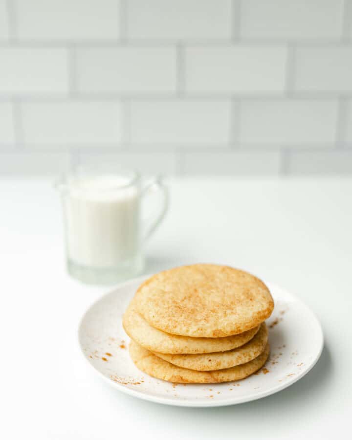 Snickerdoodles Cookie Recipe stacked on a plate with a side of milk.