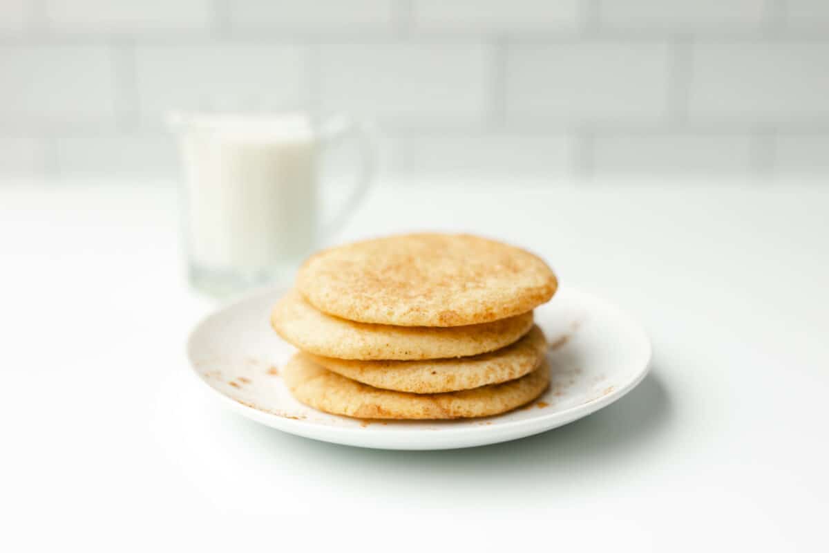 A Stack of Snickerdoodle Cookies on a plate with a glass of milk on the side.