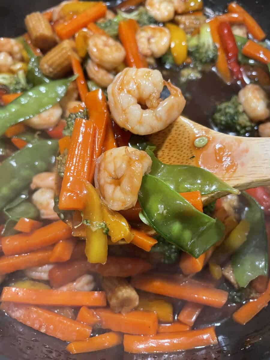 Garlic Shrimp Stir Fry in a Pan with shrimp, sliced carrots, baby corns, peas, broccoli florets, and sliced peppers. 