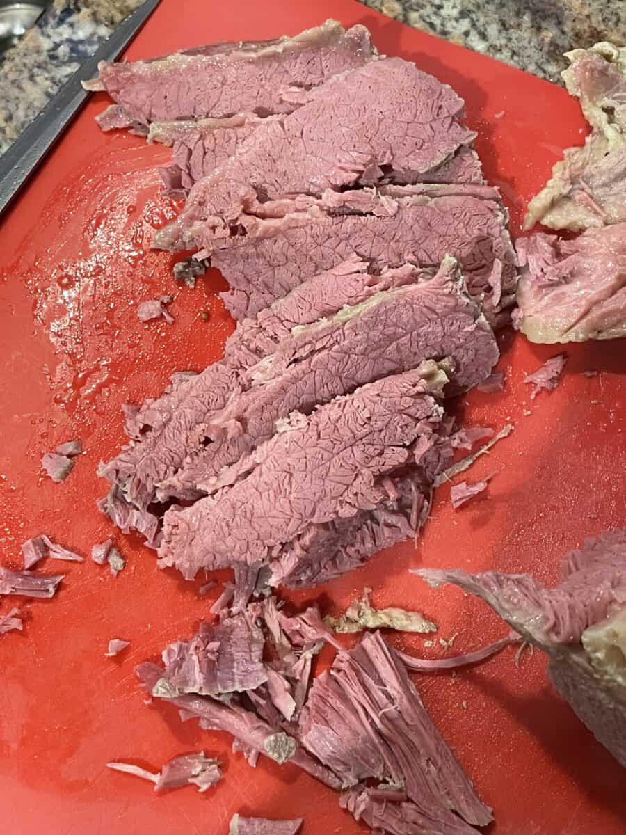 Several Slices of Slow Cooked Corned Beef on a cutting board.