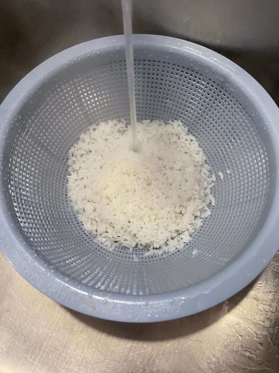 Rinsing White Rice in a Colander with Cold Water.
