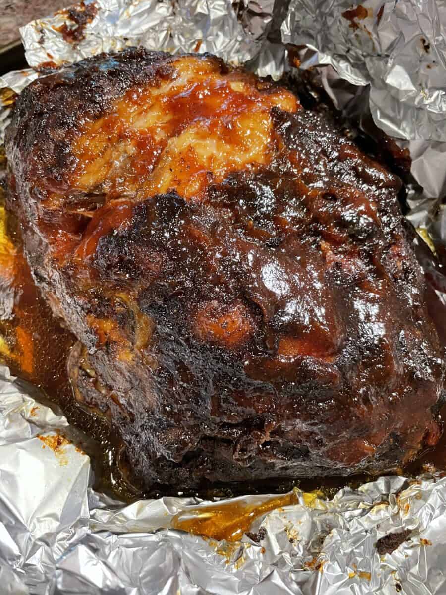 BBQ Sauce Smoked Pork Shoulder Roast wrapped in foil.