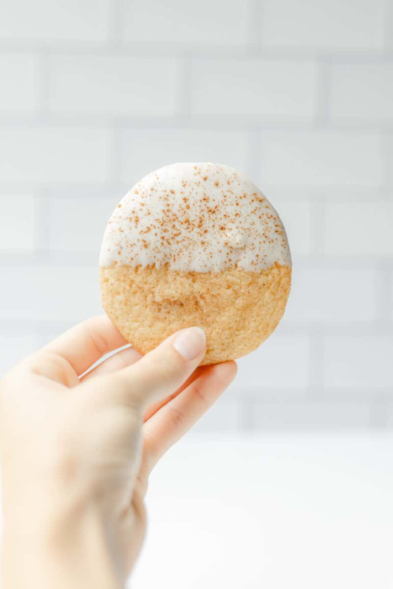 A Hand Holding a White Chocolate Covered Snickerdoodle Cookie.