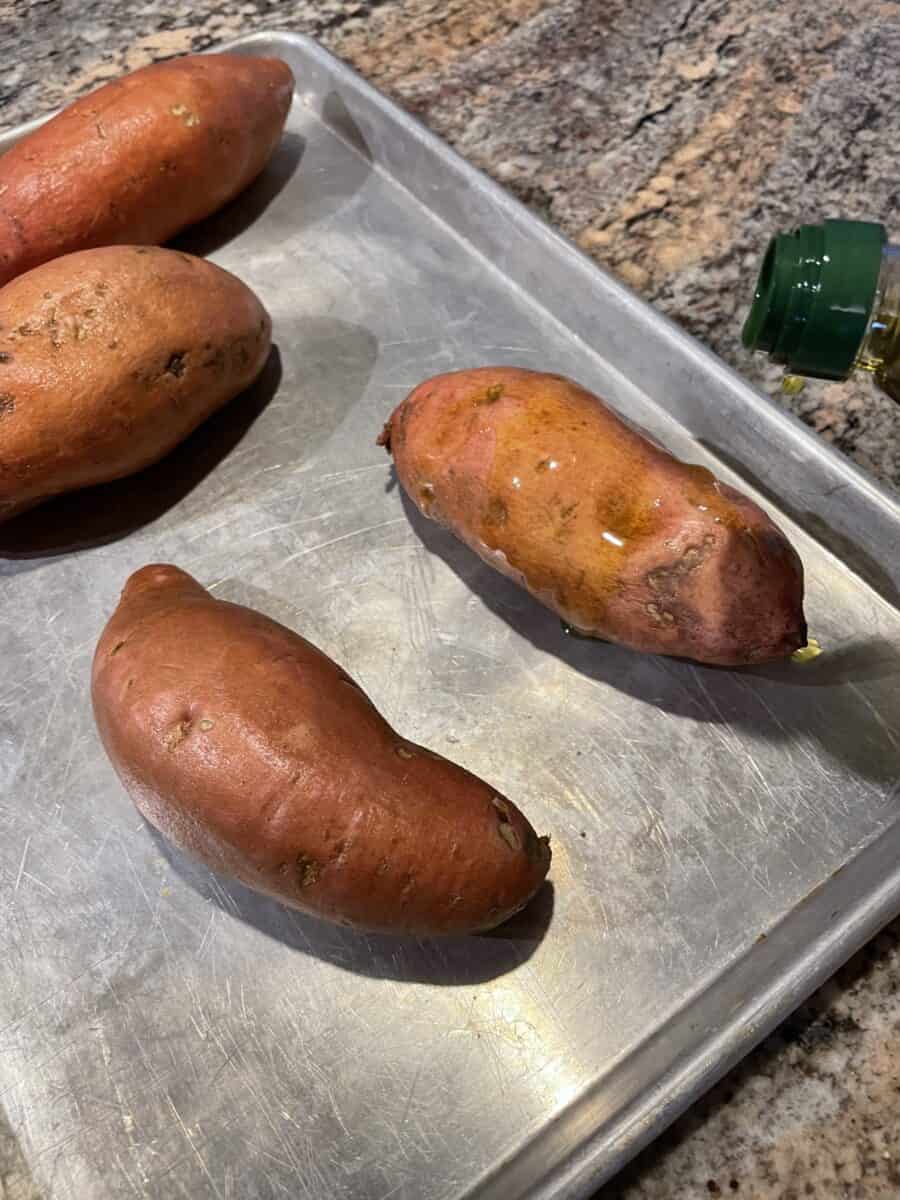 Spreading Olive Oil on top of Cleaned Sweet Potatoes.