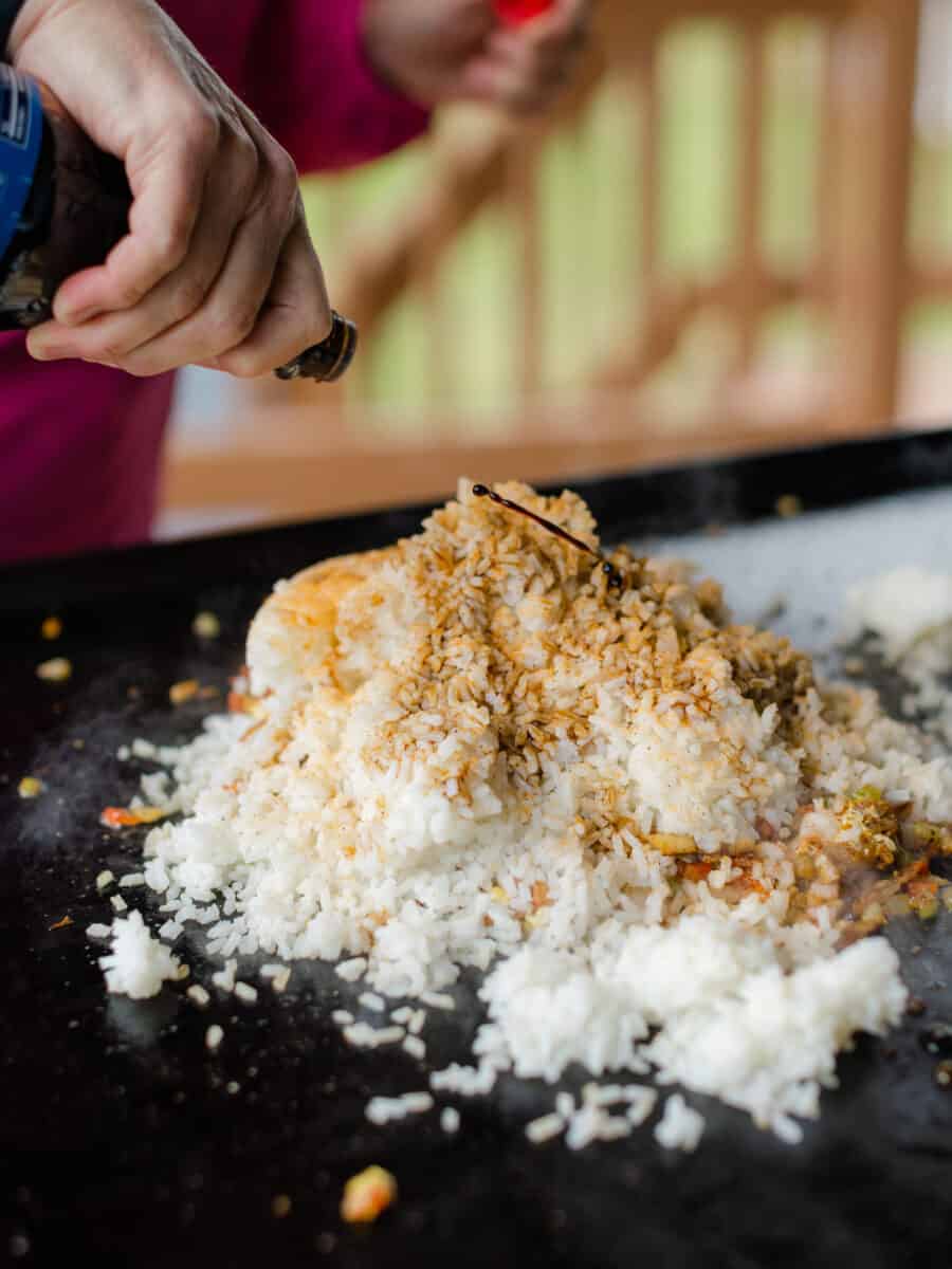Adding Cooked Rice to the Fried Rice Ingredients on a Blackstone Griddle.