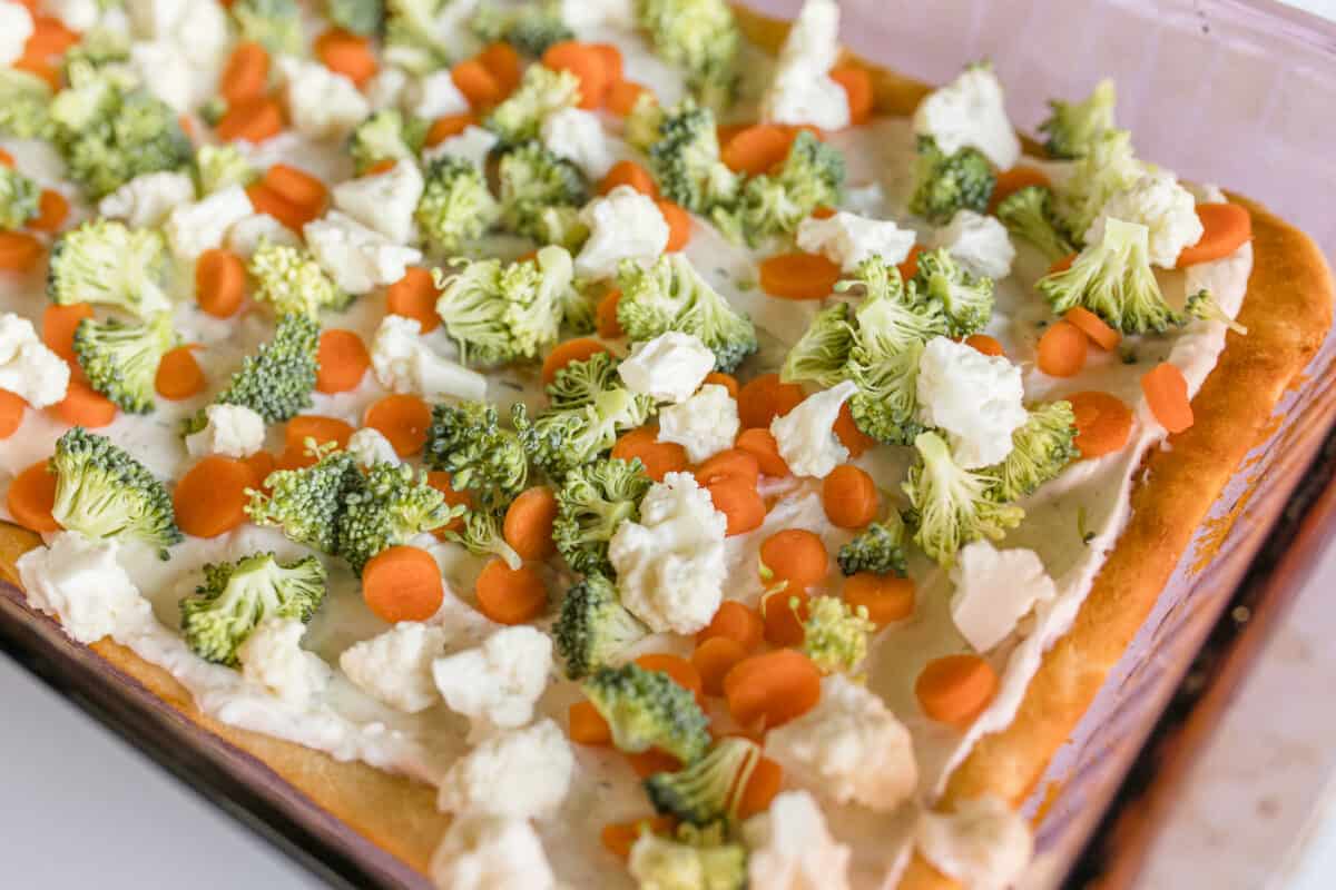 Veggie Pizza Recipe with broccoli, cauliflower, and carrots in a glass Pyrex baking pan.