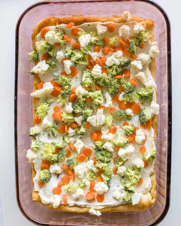 Best Veggie Pizza with broccoli, cauliflower, and carrots in a glass Pyrex baking pan.
