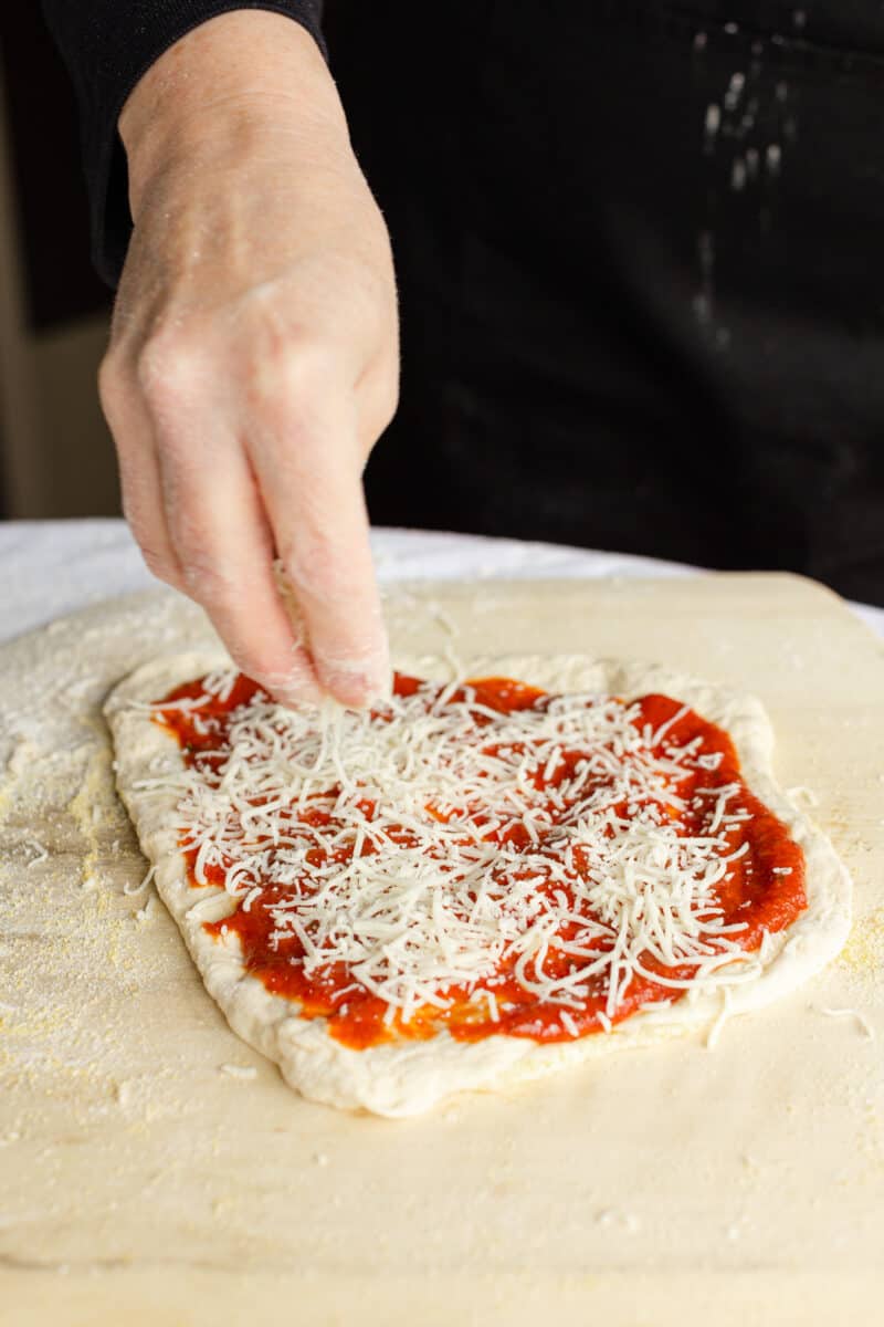 Add a Thin Layer of Shredded Mozzarella Cheese to the Pizza Sauce.