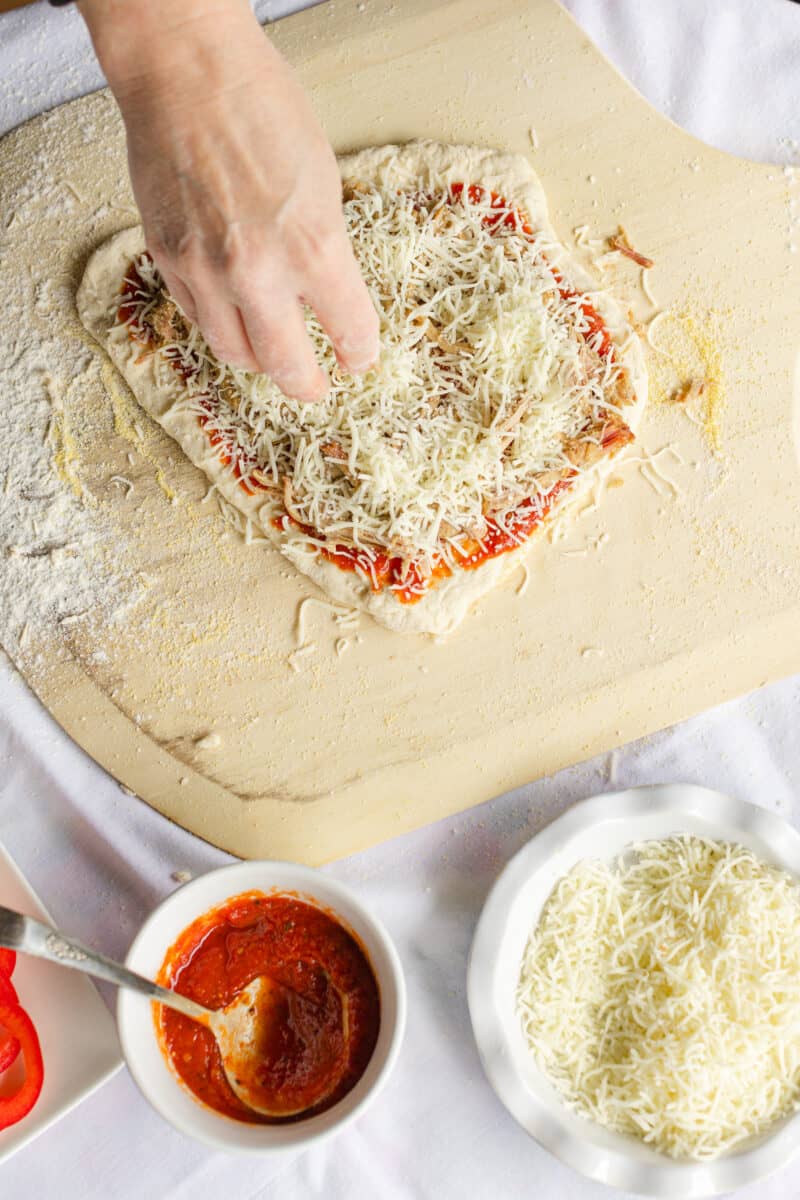 Add Another Layer of Shredded Mozzarella Cheese to the Top of the Pizza.