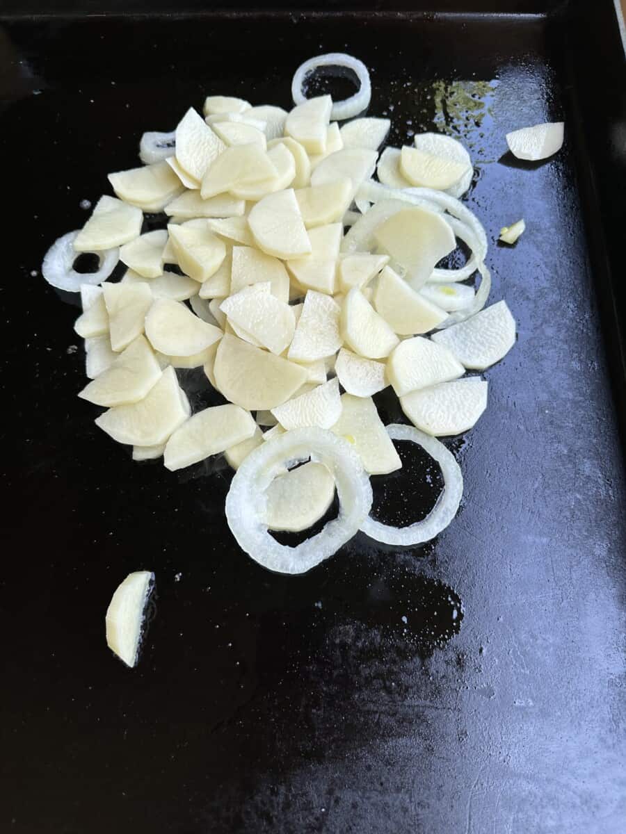 Raw Sliced Potatoes and Onions on a Griddle
