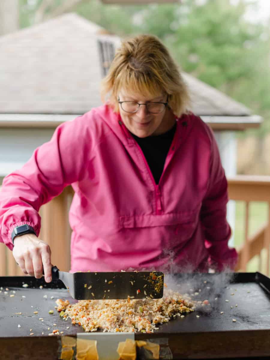 Chef Sherry Ronning Using a Griddle Spatula to Stir a Chicken and Shrimp Fried Rice Recipe on a Blackstone Griddle