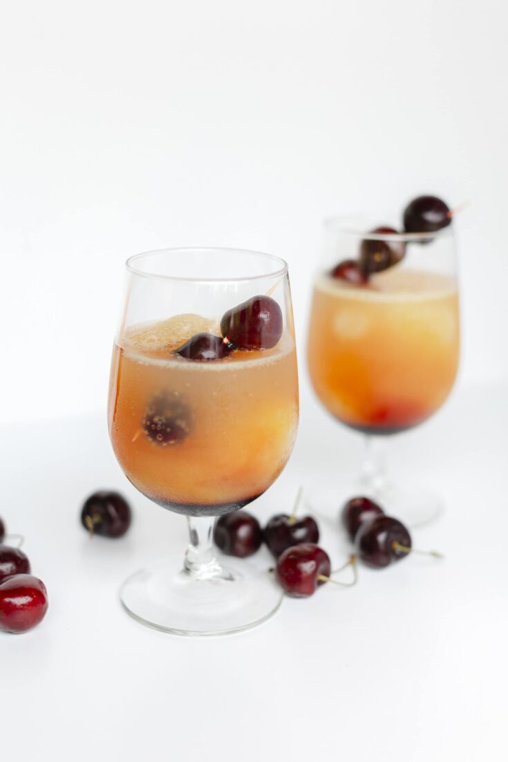 2- Cherry Slushie with Whiskey in stem glasses Garnished and surrounded with fresh cherries.