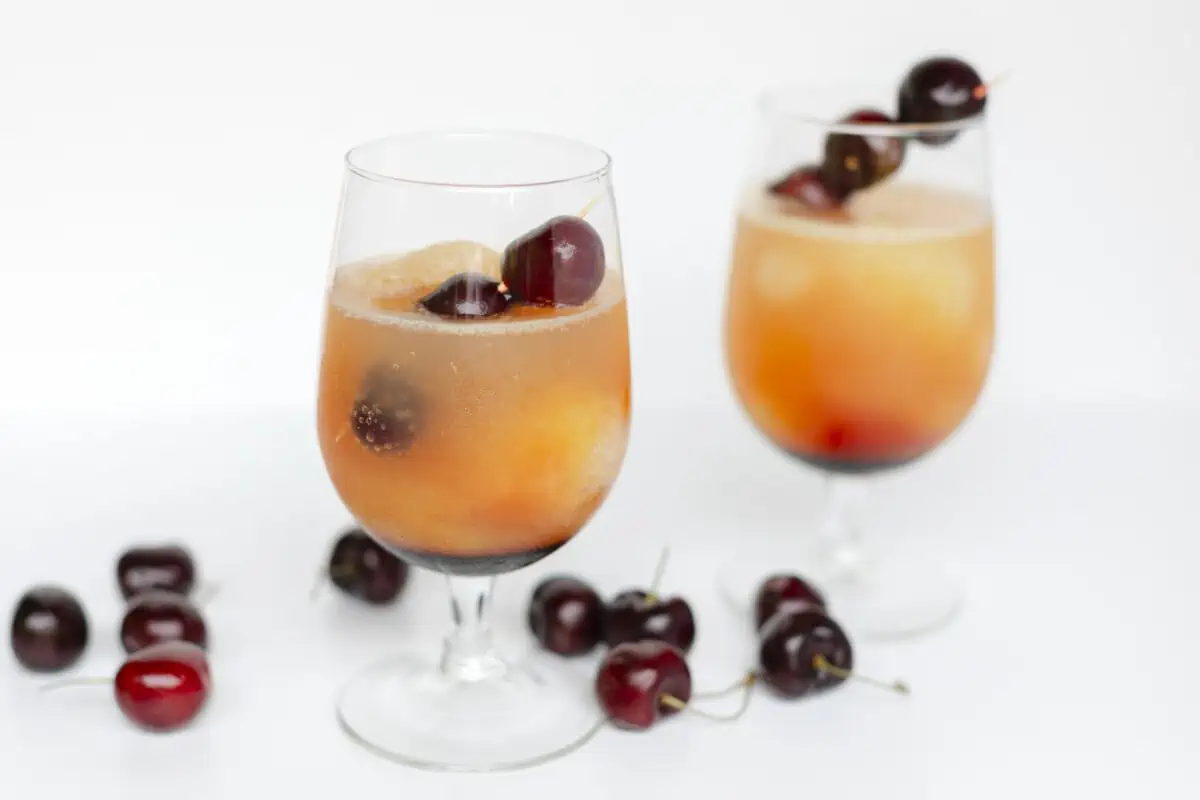 Cherry Whiskey Slush in stem glasses Garnished and surrounded with fresh cherries.