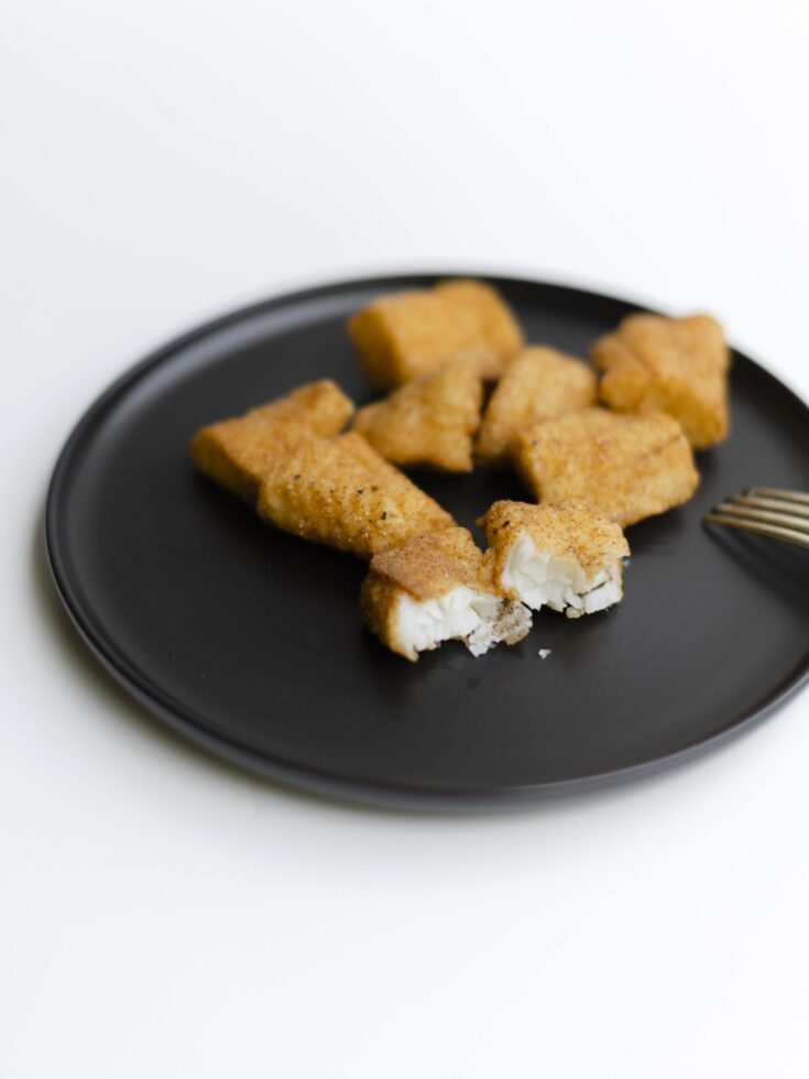 Fried Walleye Fillets on a Black Plate with a fork.