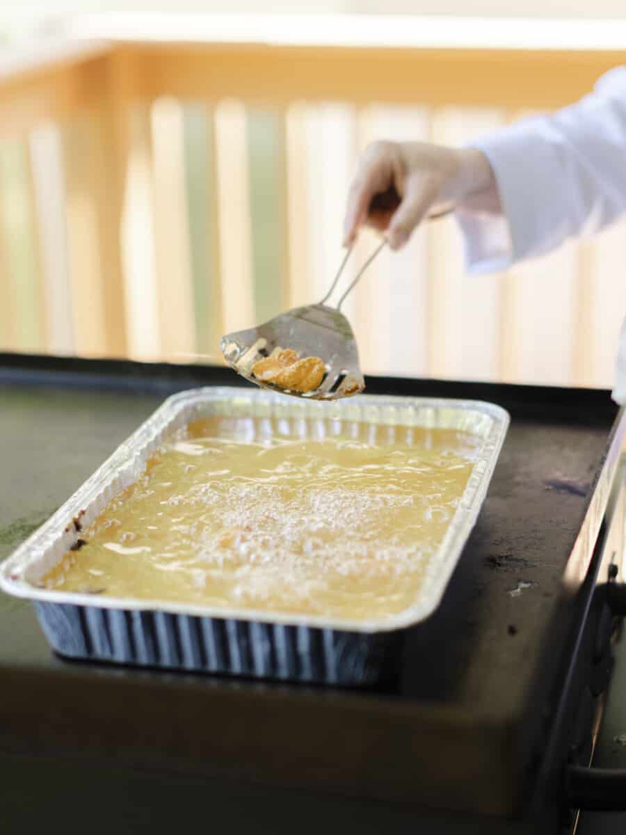 Using a Slotted Spoon to Remove Cooked Walleye Fillets From the Deep Fried Pan.