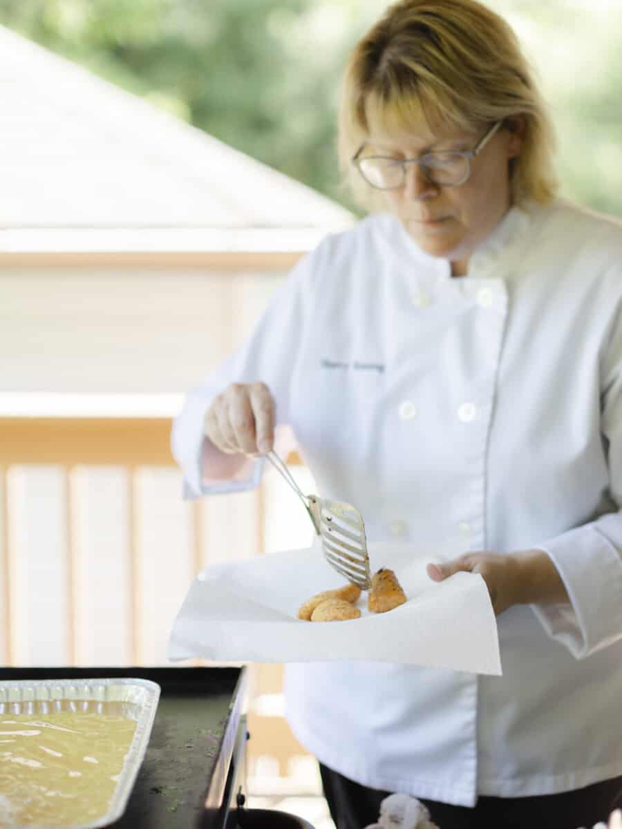 Chef Sherry Ronning Setting Fried Walleye Pieces onto a Paper Towel Lined Plate.