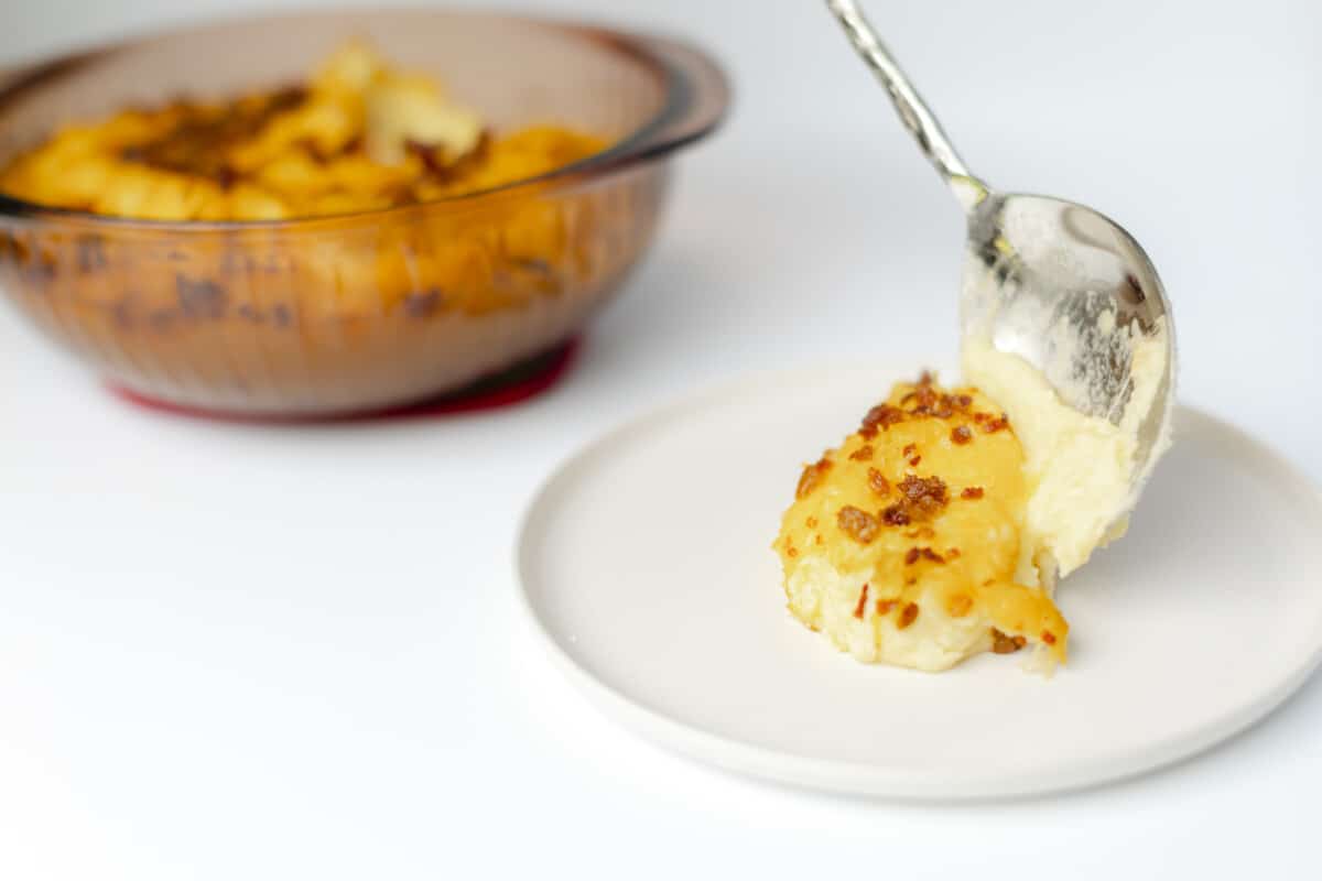 Twice Baked Mashed Potatoes Recipe in a baking dish and placed on a plate.