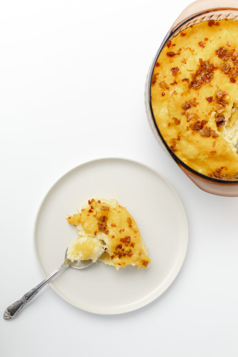 Bacon and Cheesy Mashed Potatoes in a baking dish and serving plate.