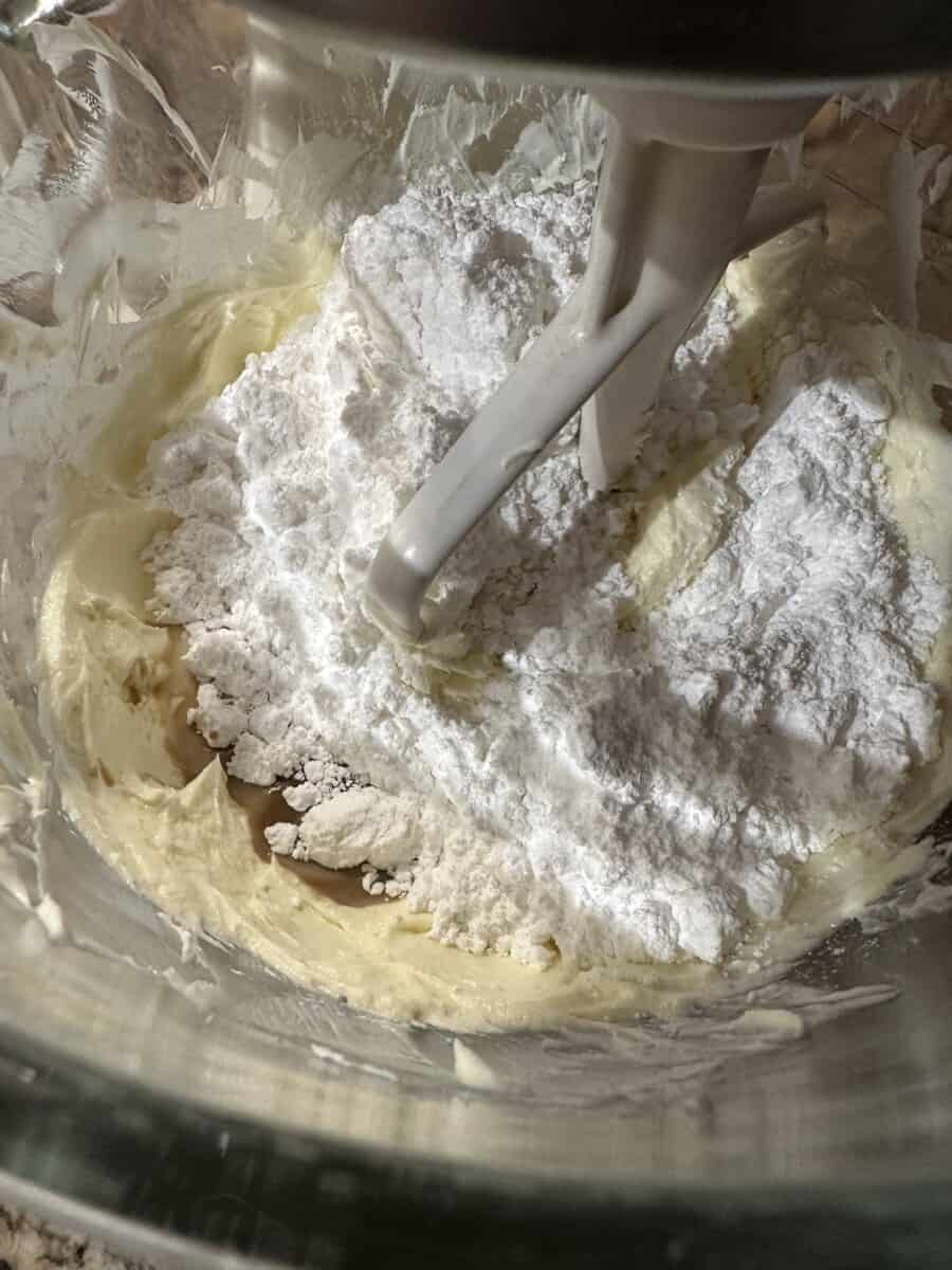Adding Powdered Sugar, Vanilla, and Milk to the Cream Cheese Mixture.