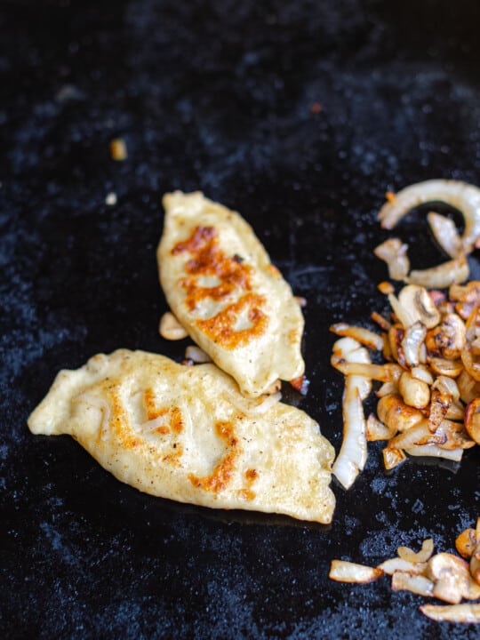 Blackstone Griddle Cabbage Pierogies with cooked mushroom and onions.