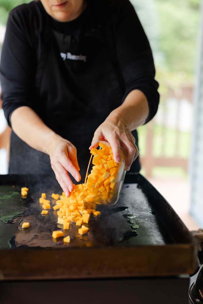 Chef Sherry Ronning Adding Cubed Butternut Squash to a Hot Blackstone Griddle