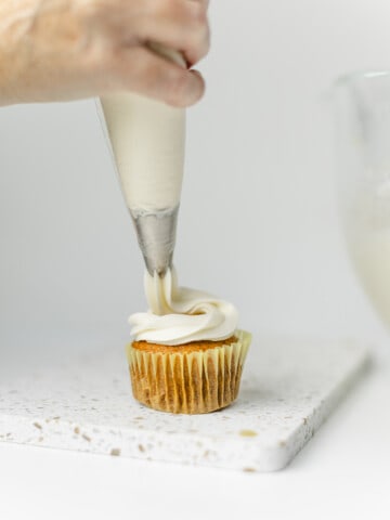 Piping the Cream Cheese Frosting Recipe onto a cupcake.