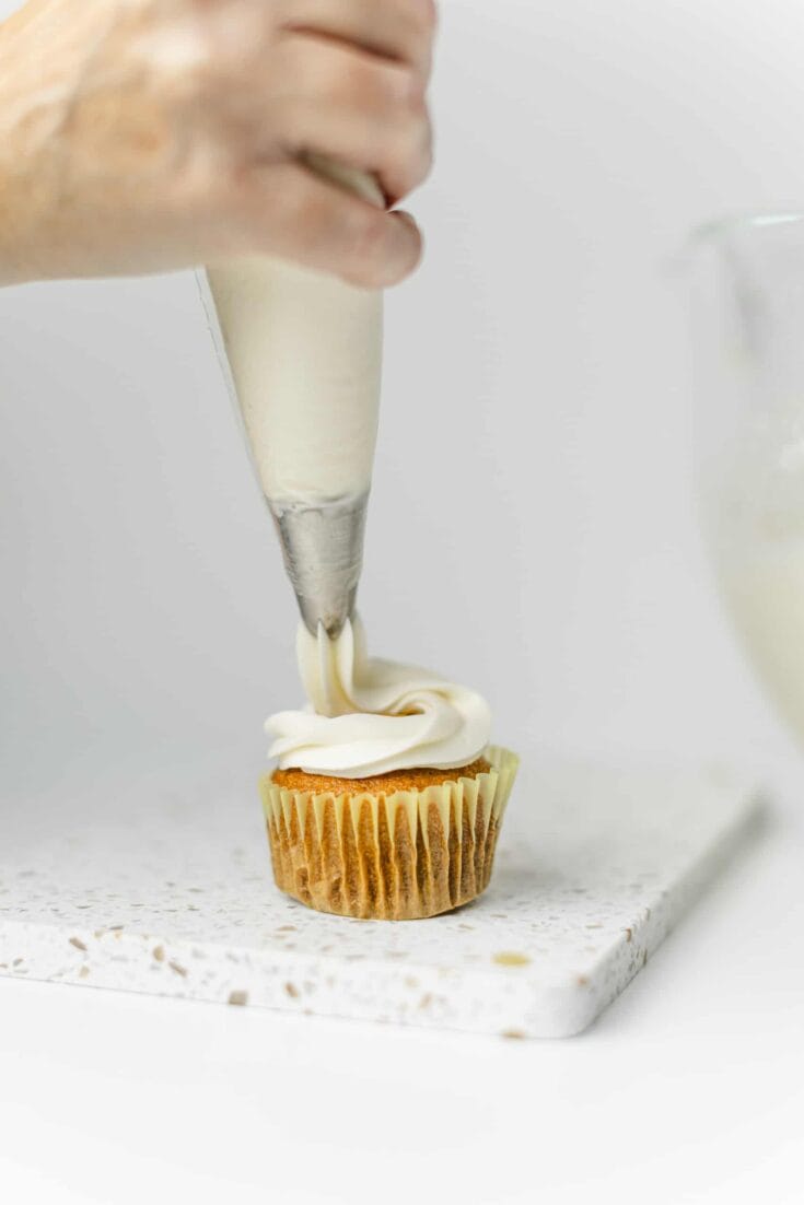 Piping the Cream Cheese Frosting Recipe onto a cupcake.