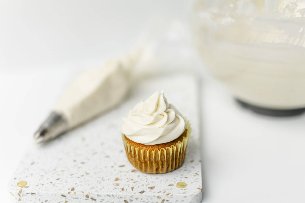 Cream Cheese Frosted Cupcake with a bowl and piping bag of frosting.