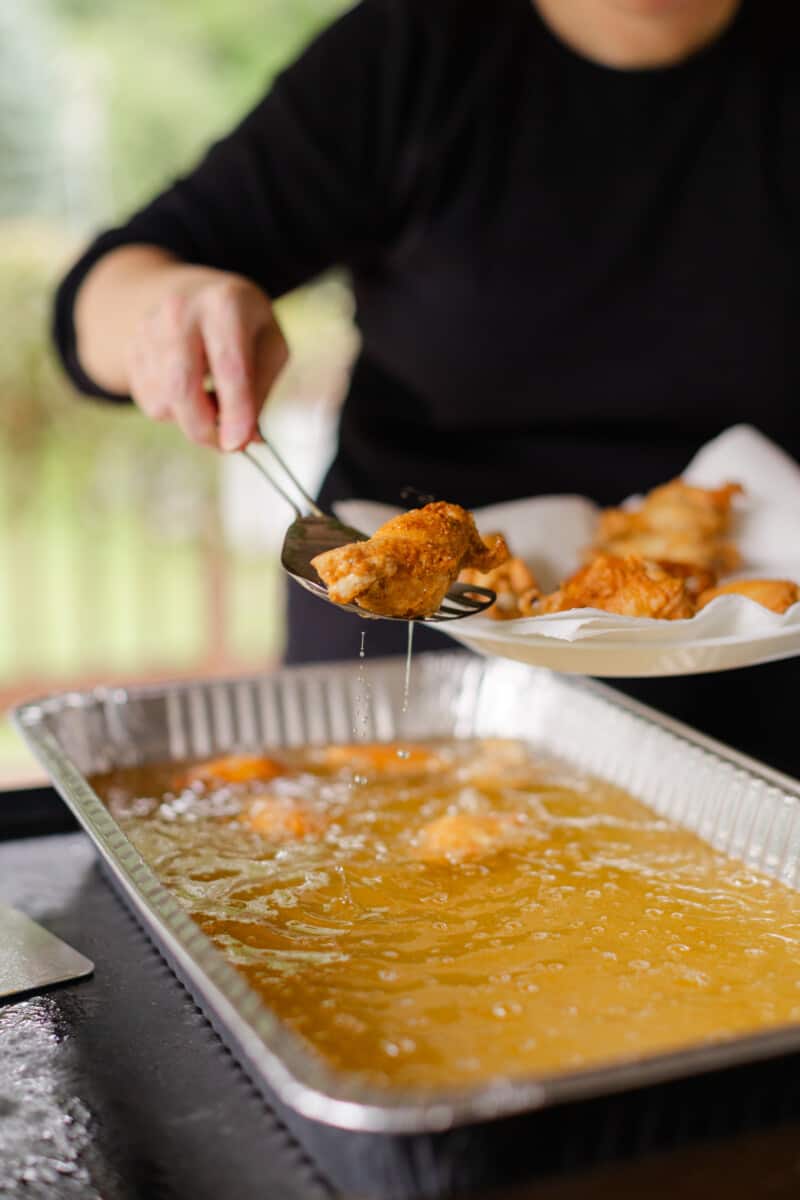Removing Fully Cooked Blackstone Deep Fried Chicken Wings from the Hot Oil to a Paper Towel lined plate.